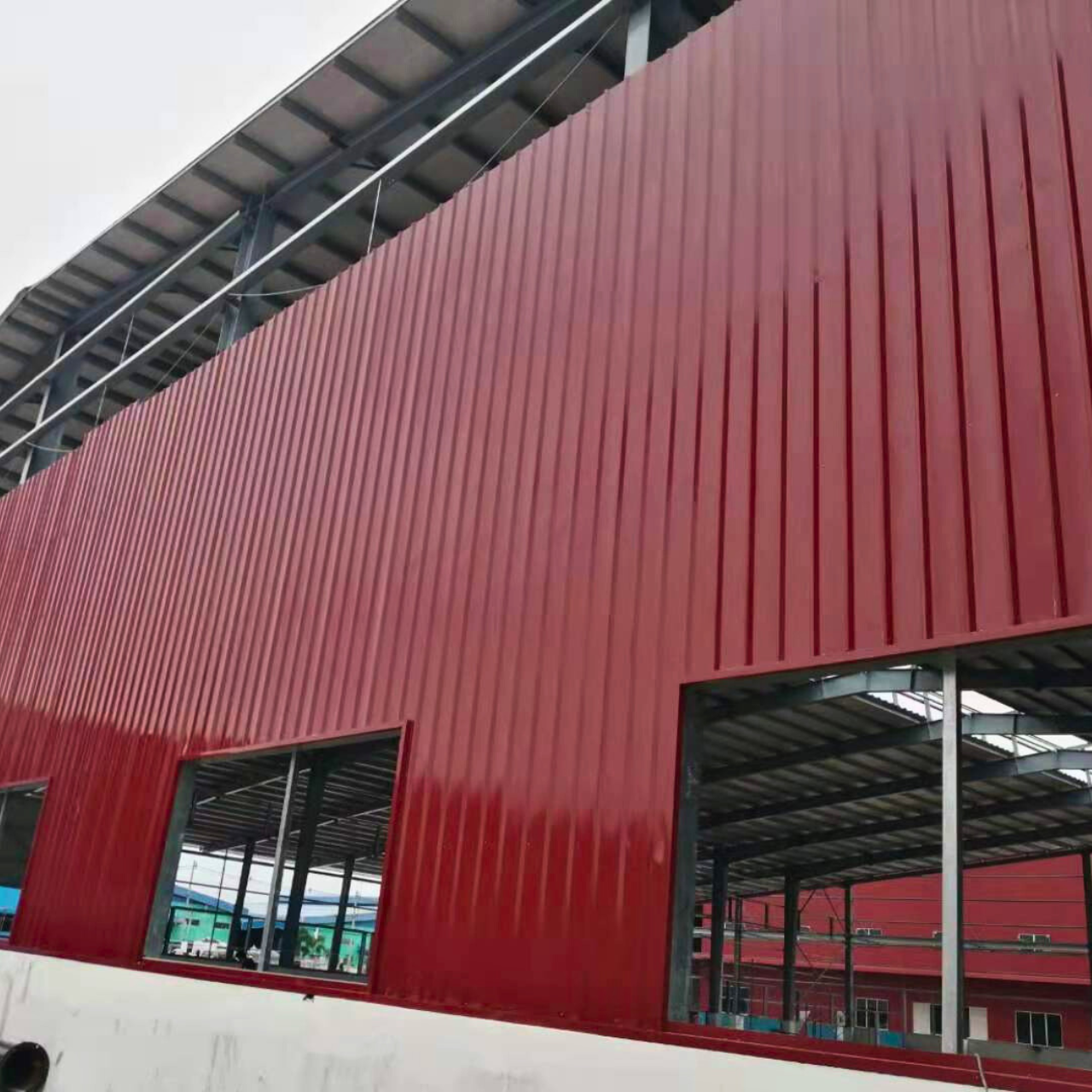 Myanmar Yi Jin is installing red exterior wall cladding on a steel structure warehouse at their project site in Yangon, Myanmar, highlighting the building's facade.