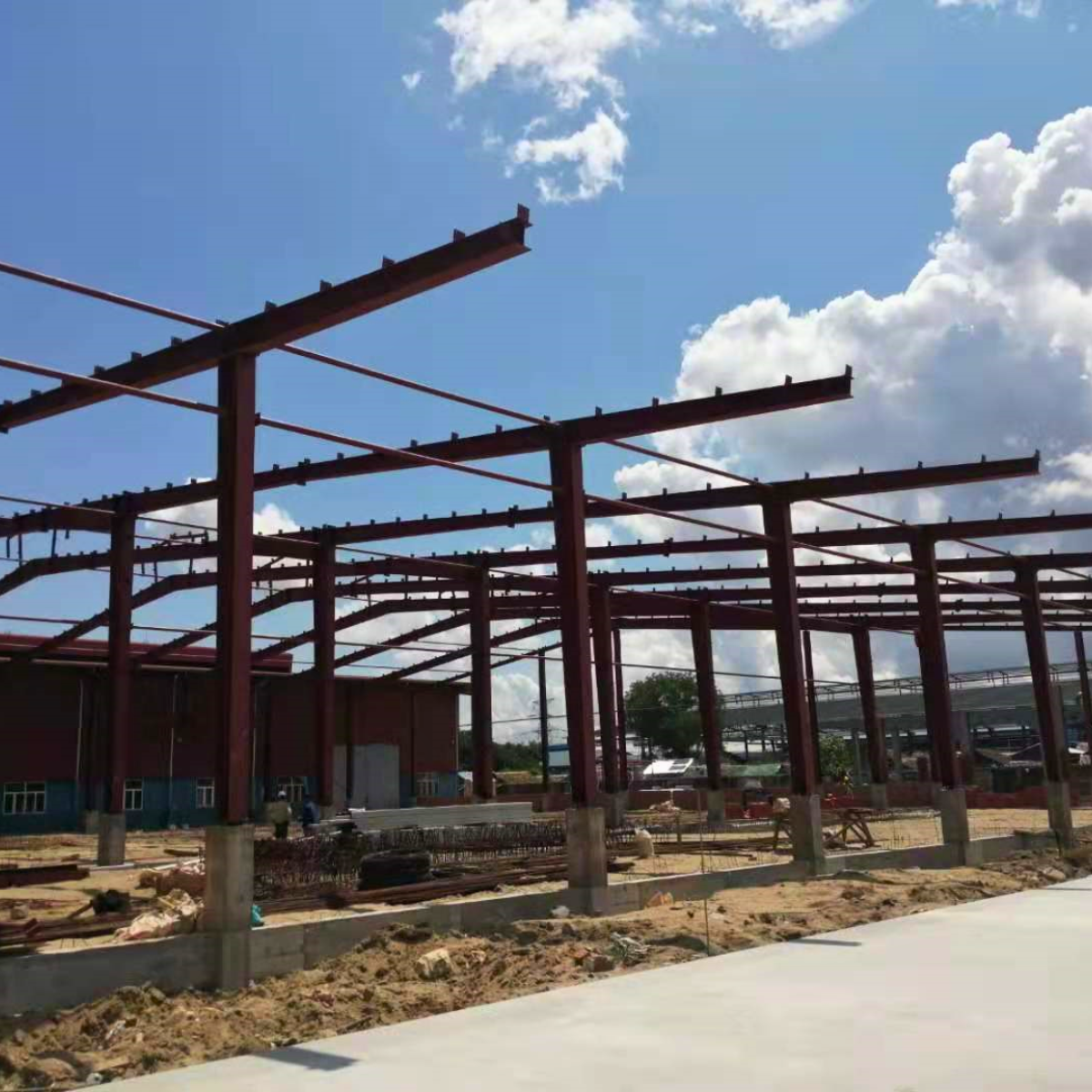 Brick wall construction underway beside a steel frame warehouse at Myanmar Yi Jin customer site, showcasing integration of masonry walls with industrial steel structure