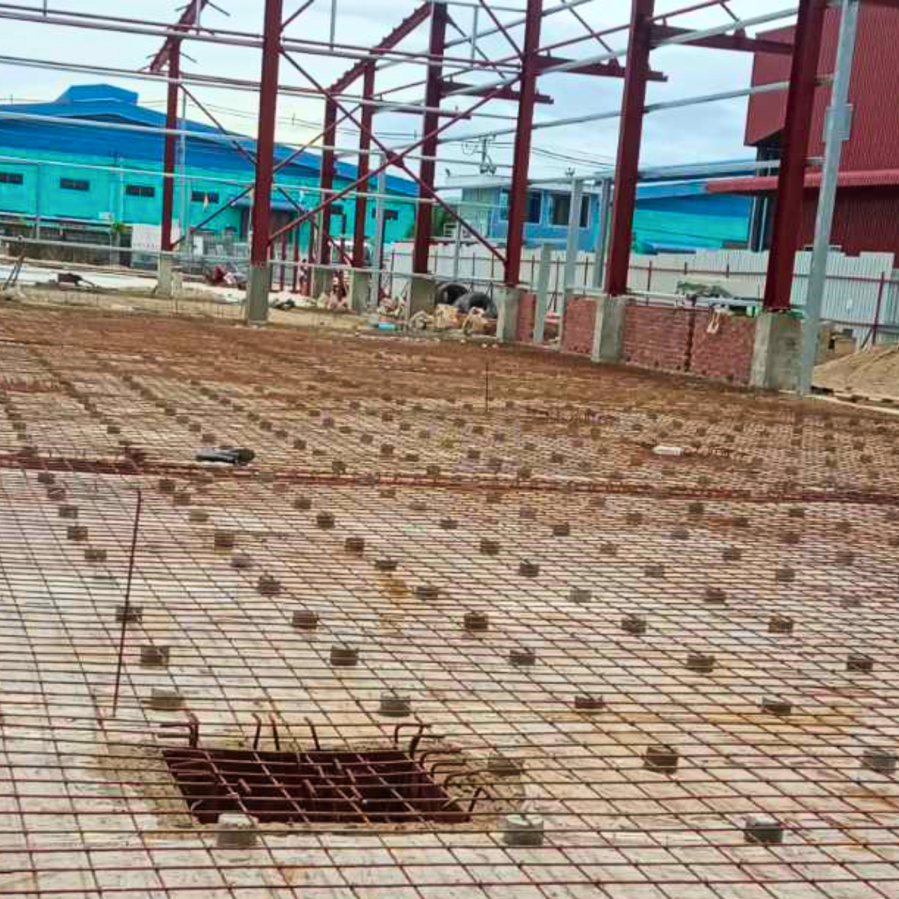 Ground slab reinforcement work in progress for a steel structure warehouse, showing rebar grid installation before concrete pouring.