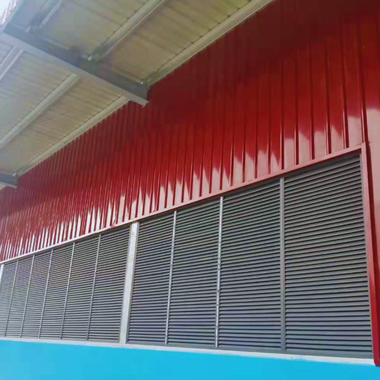 Exterior view of the finished red wall cladding and grey ventilation louvres on a Myanmar Yi Jin steel structure warehouse project site in Yangon, Myanmar.
