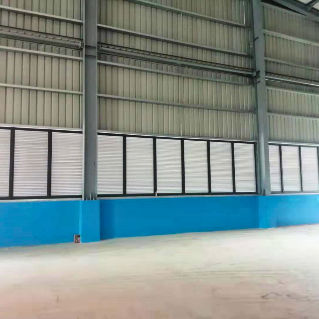 Interior view of finished wall details inside a steel structure warehouse in Yangon, Myanmar, featuring a blue painted base, louvred sections, and metal wall cladding for ventilation.