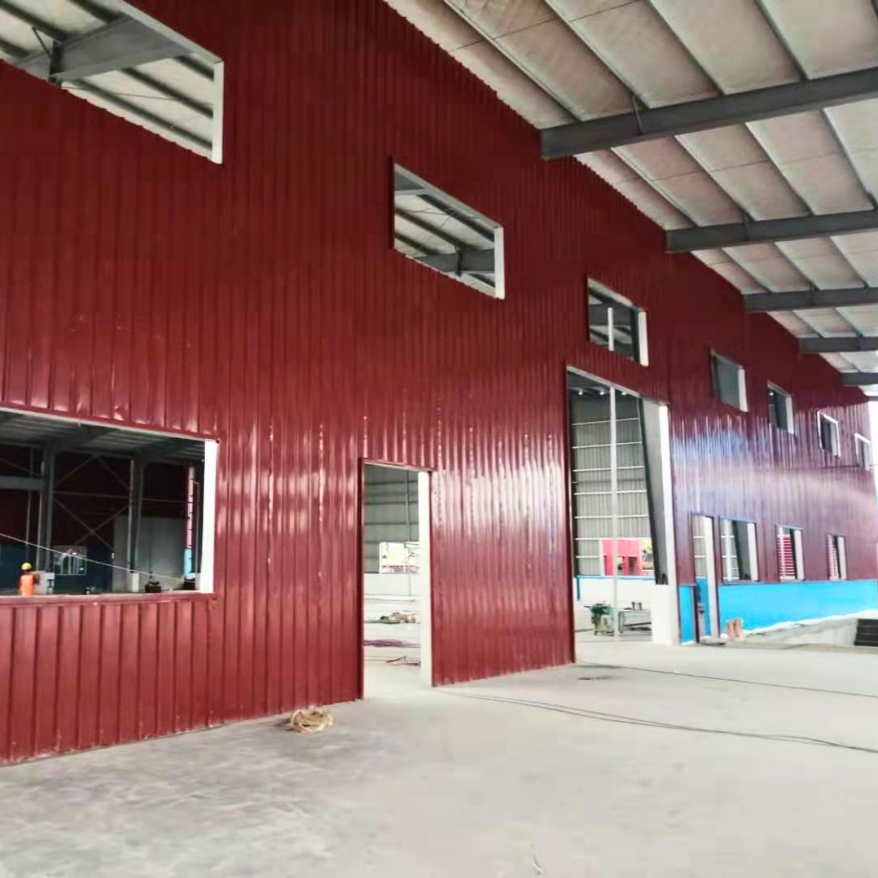 Interior view of finished red wall cladding and open window/door sections at a Myanmar Yi Jin steel warehouse project site in Yangon, Myanmar, showcasing the completed interior walls