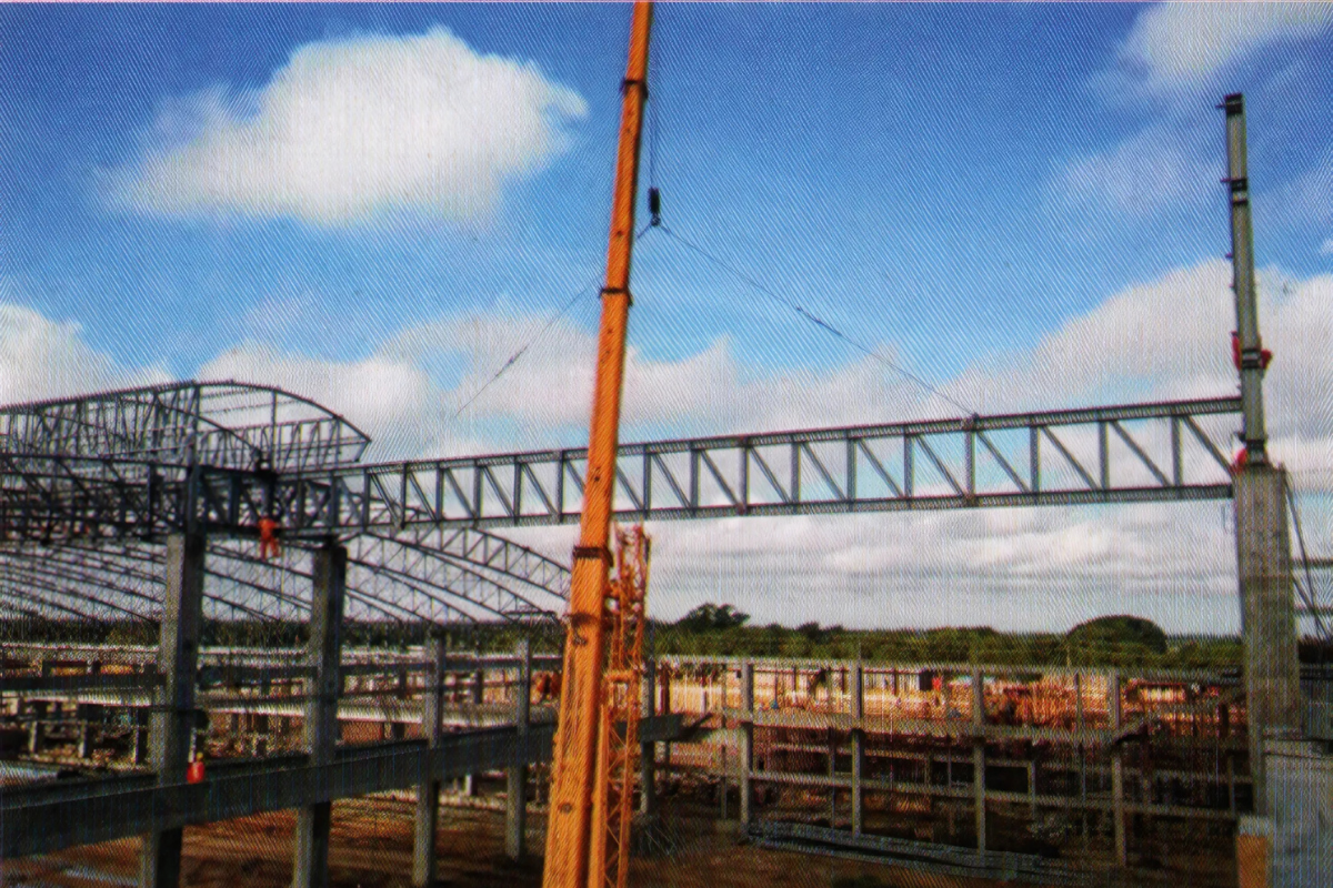 The steel structure construction of the 60,000m² Europe & Asia Commercial (EAC) warehouse in Mandalay, with various views of the arc-shaped pipe truss roof and cranes.