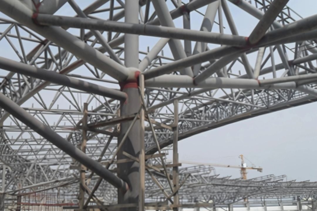 A close-up photo of the complex steel roof structure for the 2013 SEA Games stadium in Myanmar, showcasing the intricate truss work and support beams installed by Myanmar Yi Jin.