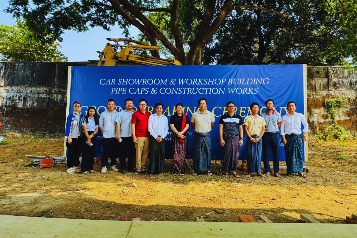 The project team and stakeholders standing in front of a blue "Groundbreaking Ceremony" banner for Performance Auto International’s car showroom and workshop building, featuring an excavator in the background.