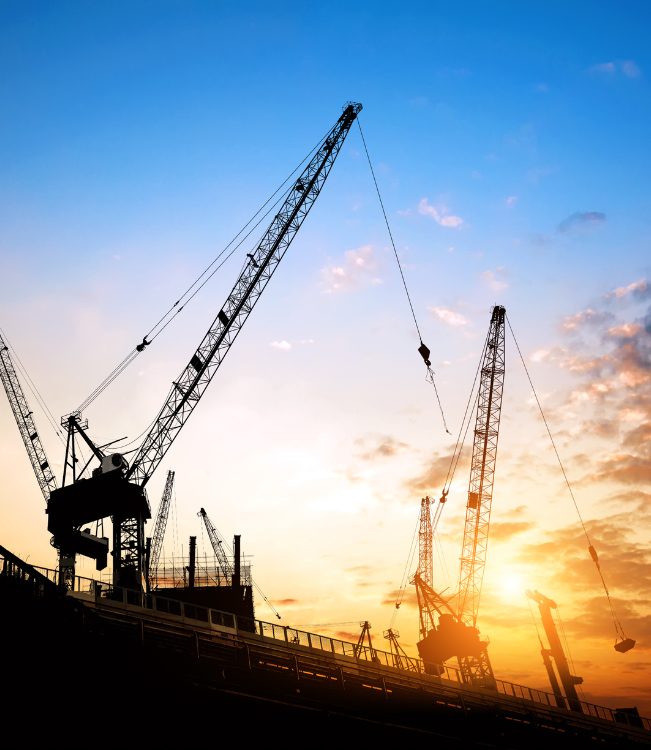 Industrial silhouettes of heavy-duty machinery during golden hour, representing the scale and vision of Myanmar Yi Jin's engineering projects.