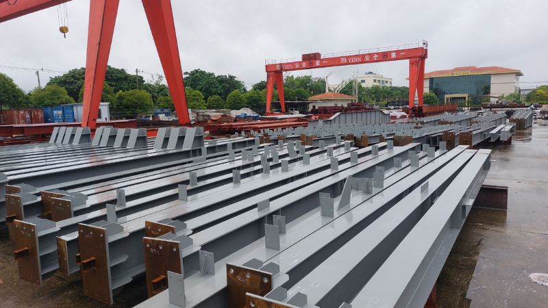 Fabricated steel columns and structural components stored at Myanmar Yi Jin factory yard ready for shipment to Mandalay Business City Development project site.