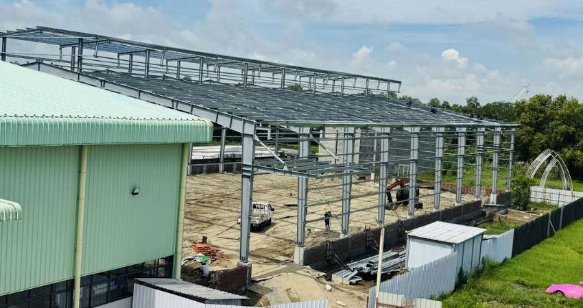Ongoing steel structure warehouse factory extension showing roof trusses and columns for Performance Auto International Co. Ltd.